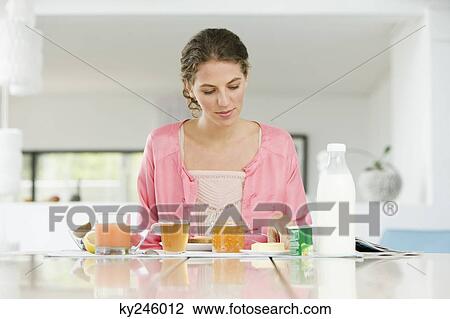 Woman having breakfast at a table View Large Photo Image Stock Image - Woman having breakfast at a table. Fotosearch
