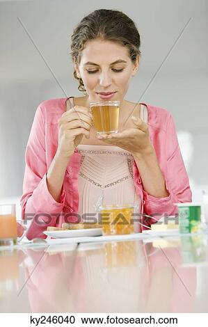 Stock Image - Woman having breakfast at a table. Fotosearch