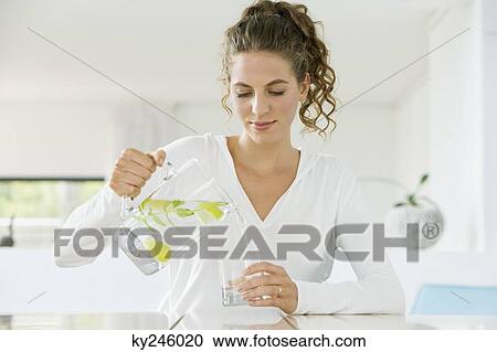 Woman pouring lemonade into a glass from a jug View Large Photo Image Stock Image - Woman pouring lemonade into a glass from a jug. Fotosearch