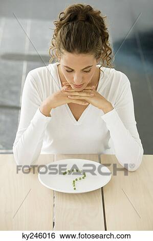 Woman sitting at a table with peas in question mark shape on a plate View Large Photo Image Stock Photograph - Woman sitting at a table with peas in question mark shape on a plate. Fotosearch