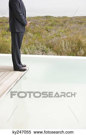 Businessman standing on the platform of an infinity pool View Large Photo Image Stock Photography - Businessman standing on the platform of an infinity pool. Fotosearch