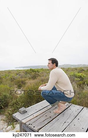 Man crouching on a boardwalk and thinking View Large Photo Image Stock Image - Man crouching on a boardwalk and thinking. Fotosearch