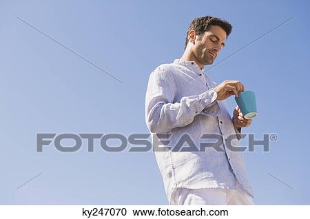 Man holding a cup of coffee on the beach View Large Photo Image Stock Image - Man holding a cup of coffee on the beach. Fotosearch