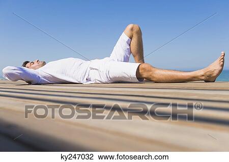 Man lying on a boardwalk on the beach View Large Photo Image Stock Image - Man lying on a boardwalk on the beach. Fotosearch