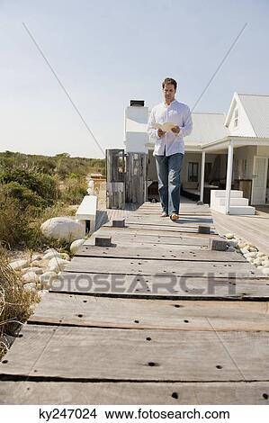 Man reading a book and walking on a boardwalk View Large Photo Image Picture - Man reading a book and walking on a boardwalk. Fotosearch