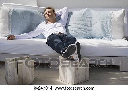 Man resting on a couch View Large Photo Image Picture - Man resting on a couch. Fotosearch
