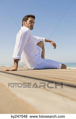 Man sitting on the beach View Large Photo Image Stock Photo - Man sitting on the beach. Fotosearch