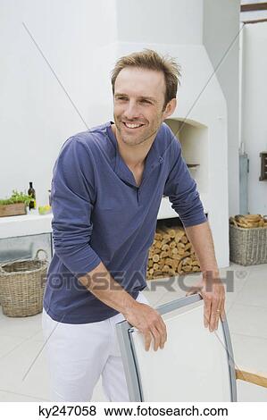 Man standing behind a chair and smiling View Large Photo Image Stock Photo - Man standing behind a chair and smiling. Fotosearch