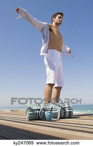 Man standing on a boardwalk with his arm outstretched View Large Photo Image Stock Photo - Man standing on a boardwalk with his arm outstretched. Fotosearch
