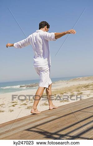 Man walking on a boardwalk on the beach View Large Photo Image Stock Image - Man walking on a boardwalk on the beach. Fotosearch