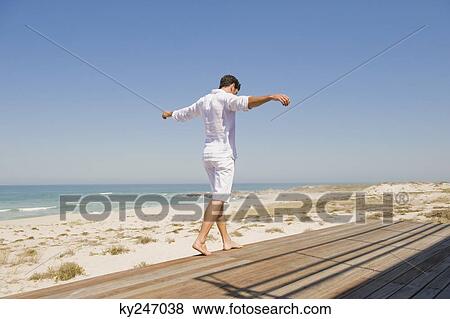 Man walking on a boardwalk on the beach View Large Photo Image Stock Photo - Man walking on a boardwalk on the beach. Fotosearch