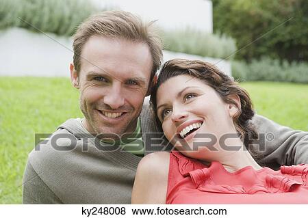 Couple resting in a lawn and smiling View Large Photo Image Stock Photo - Couple resting in a lawn and smiling. Fotosearch
