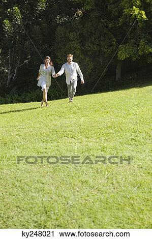 Stock Image - Couple running on grass. Fotosearch