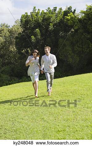 Couple running on grass View Large Photo Image Stock Photo - Couple running on grass. Fotosearch
