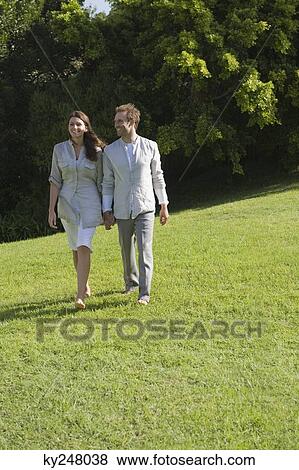 Couple walking on grass and smiling View Large Photo Image Stock Photo - Couple walking on grass and smiling. Fotosearch