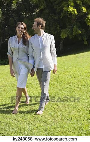 Couple walking on grass and smiling View Large Photo Image Stock Photo - Couple walking on grass and smiling. Fotosearch