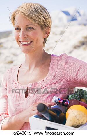 Stock Photography - Woman carrying a crate on the beach. Fotosearch