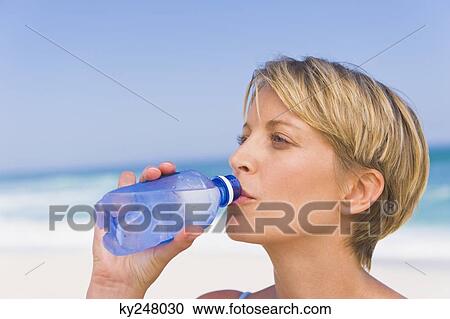 Woman drinking water on the beach View Large Photo Image Stock Image - Woman drinking water on the beach. Fotosearch