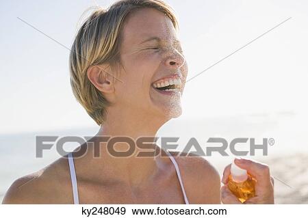 Woman holding a perfume bottle and smiling View Large Photo Image Stock Photo - Woman holding a perfume bottle and smiling. Fotosearch