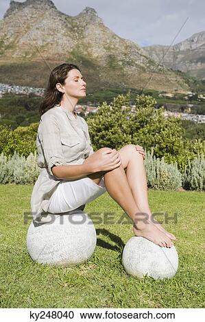 Stock Image - Woman meditating on round stones. Fotosearch