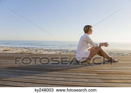 Woman sitting on a boardwalk View Large Photo Image Stock Image - Woman sitting on a boardwalk. Fotosearch