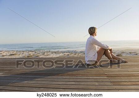 Woman sitting on a boardwalk View Large Photo Image Stock Photography - Woman sitting on a boardwalk. Fotosearch