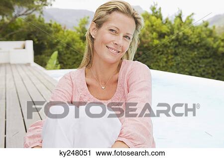 Woman sitting on a terrace and smiling View Large Photo Image Stock Image - Woman sitting on a terrace and smiling. Fotosearch
