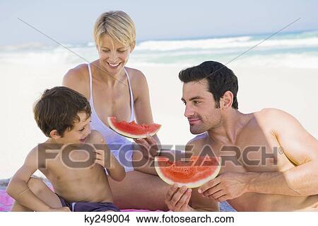 Family enjoying watermelon on the beach View Large Photo Image Picture - Family enjoying watermelon on the beach. Fotosearch