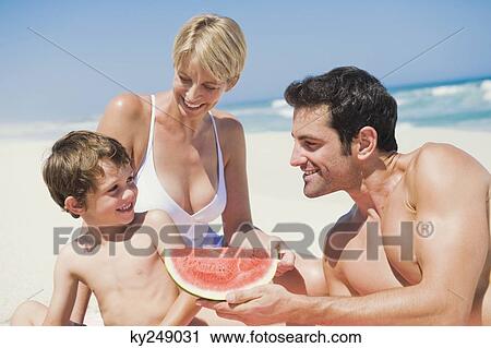 Family enjoying watermelon on the beach View Large Photo Image Stock Image - Family enjoying watermelon on the beach. Fotosearch
