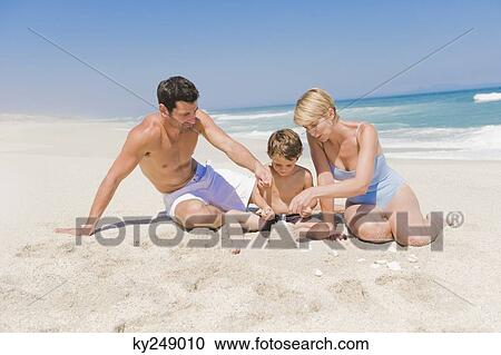 Family making a sand castle on the beach View Large Photo Image Stock Image - Family making a sand castle on the beach. Fotosearch
