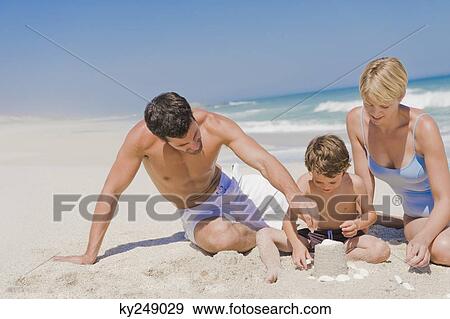 Family making a sand castle on the beach View Large Photo Image Stock Photo - Family making a sand castle on the beach. Fotosearch