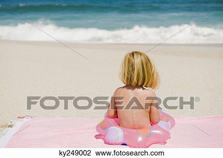 Girl sitting with an inflatable ring on the beach View Large Photo Image Stock Image - Girl sitting with an inflatable ring on the beach. Fotosearch