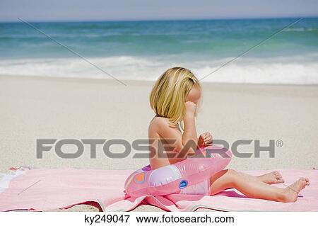 Girl sitting with an inflatable ring on the beach and crying View Large Photo Image Stock Photo - Girl sitting with an inflatable ring on the beach and crying. Fotosearch
