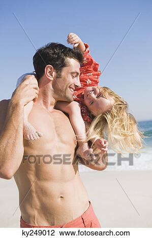 Man carrying his daughter on his shoulders on the beach View Large Photo Image Stock Image - Man carrying his daughter on his shoulders on the beach. Fotosearch
