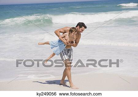 Man playing with his son on the beach View Large Photo Image Stock Photograph - Man playing with his son on the beach. Fotosearch