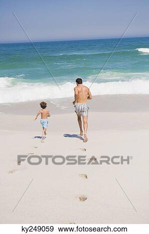 Man running with his son on the beach View Large Photo Image Stock Photo - Man running with his son on the beach. Fotosearch
