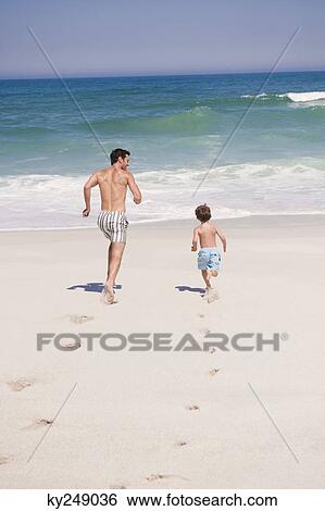 Man running with his son on the beach View Large Photo Image Stock Photograph - Man running with his son on the beach. Fotosearch