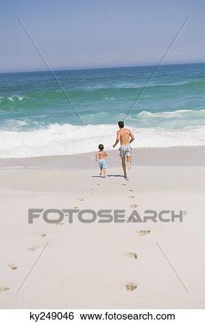Man running with his son on the beach View Large Photo Image Stock Photograph - Man running with his son on the beach. Fotosearch