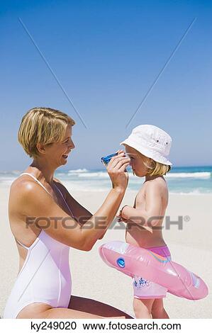 Stock Image - Woman putting on sunglasses on her daughter's face. Fotosearch