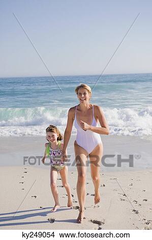 Woman running on the beach with her daughter View Large Photo Image Picture - Woman running on the beach with her daughter. Fotosearch