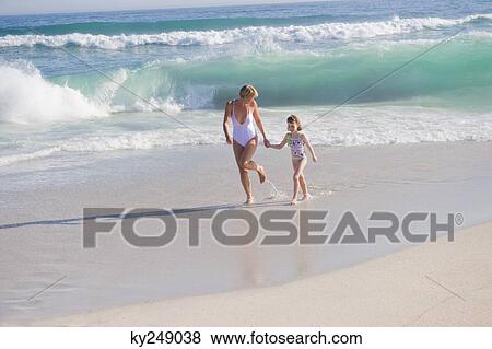 Woman running on the beach with her daughter View Large Photo Image Stock Photo - Woman running on the beach with her daughter. Fotosearch