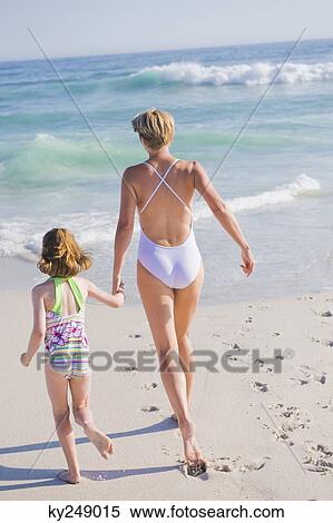 Stock Photography - Woman running on the beach with her daughter. Fotosearch