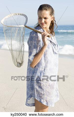 Woman carrying a fishing net on the beach View Large Photo Image Stock Image - Woman carrying a fishing net on the beach. Fotosearch