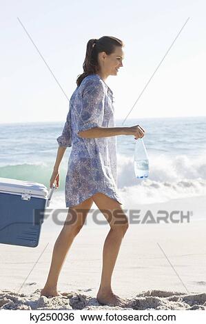 Woman carrying an ice box on the beach View Large Photo Image Stock Photograph - Woman carrying an ice box on the beach. Fotosearch