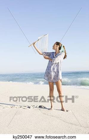 Woman holding a fishing net on the beach View Large Photo Image Stock Photo - Woman holding a fishing net on the beach. Fotosearch