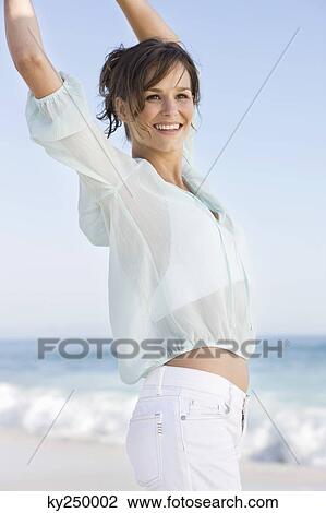 Stock Image - Woman jumping on the beach and smiling. Fotosearch