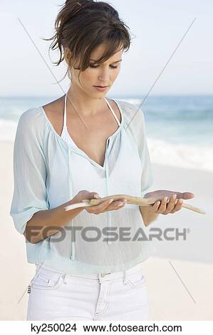Woman looking at sticks on the beach View Large Photo Image Picture - Woman looking at sticks on the beach. Fotosearch