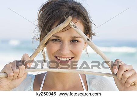 Stock Photograph - Woman making triangle shape with sticks. Fotosearch