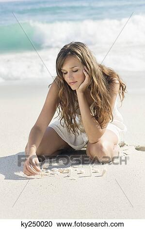 Woman playing with seashells on the beach View Large Photo Image Stock Image - Woman playing with seashells on the beach. Fotosearch