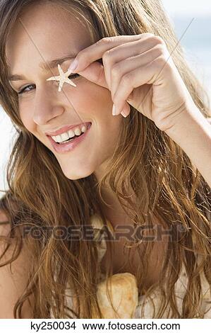 Woman showing a starfish and smiling View Large Photo Image Picture - Woman showing a starfish and smiling. Fotosearch